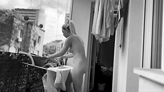A chubby woman hangs out the laundry on the balcony for neighbors to watch