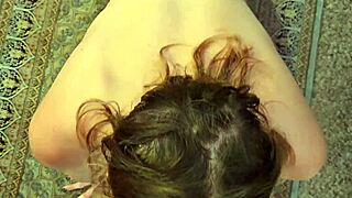 A nerdy wife with glasses kneels to service her partner closely, focusing on intimate connection.