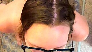 A nerdy wife with glasses kneels to service her partner closely, focusing on intimate connection.